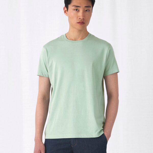 Camiseta básica ecológica unisex en verde salvia, vista de frente con modelo